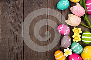 Easter eggs and flower decoration side border against a dark rustic wood background