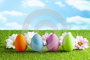 Easter eggs and flowers on the grass and blue sky background