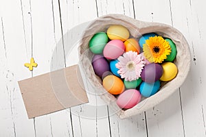 Easter eggs and gerbera flowers in heart shaped basket