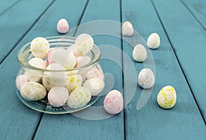 Easter eggs in glass pot on bright azure wooden planks toned selective focus