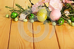 Easter eggs, grass, flowers, candy, ribbon against backdrop pale