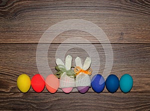 Easter eggs hand painted with knitted bunny hats over wooden background with copy space . Happy Easter