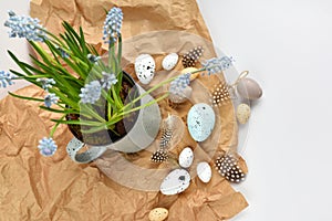 Easter eggs and light blue muscari flowers in cup on a white table. Easter still life. Top view