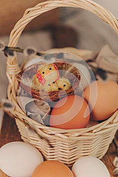Easter eggs with little yelow chick toys in basket, rustic style