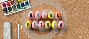 Easter eggs with message HAPPY EASTER in Italian surrounded by brushes and water color boxes