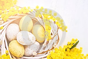 Easter eggs and mimosa wreath on a white background. Flat lay, copy space