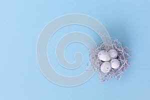 Easter eggs in nest on the blue background.Flat lay style.