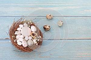Easter eggs in nest on the blue table background.Flat lay style.