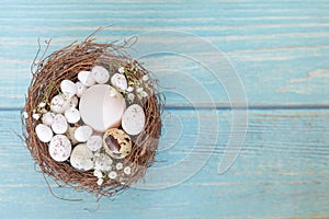 Easter eggs in nest on the blue table background.Flat lay style.