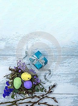 Easter eggs in the nest and a gift. Blue gift box on a gray background