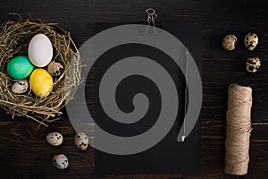 Easter eggs in nest, scissors and thread on a black background