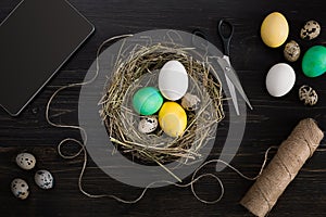 Easter eggs in nest, scissors and thread on a black background