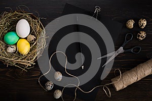 Easter eggs in nest, scissors and thread on a black background