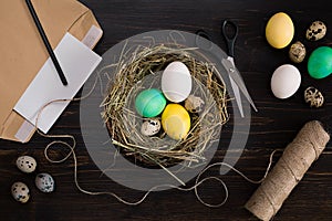 Easter eggs in nest, scissors and thread on a black background