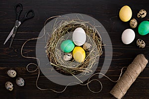 Easter eggs in nest, scissors and thread on a black background