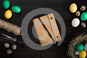 Easter eggs in nest, scissors and thread on a black background