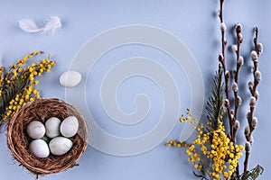 Easter eggs in nest and spring flowers on blue holiday background. Greeting card for Happy Easter. Flat lay, top view