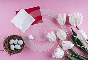 Easter eggs in nest and tulip flowers on spring background. Top view with copy space. Happy Easter card