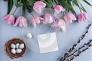 Easter eggs in nest and tulip flowers on spring background. Top view with copy space. Happy Easter card