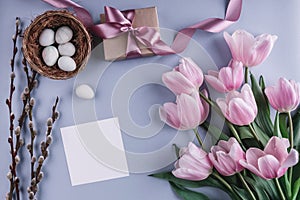 Easter eggs in nest and tulips flowers on blue background with card and gift. Happy Easter. Top view with copy space