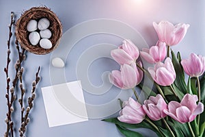 Easter eggs in nest and tulips flowers on blue background with card. Happy Easter. Top view with copy space