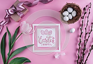 Easter eggs in nest and tulips flowers on pink background with Easter card. Waiting for spring.