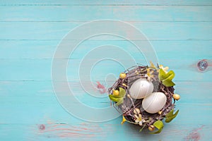 Easter eggs in nest of twigs on vintage azure wooden background