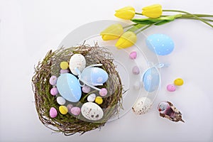 Easter eggs in nest on white wood table.