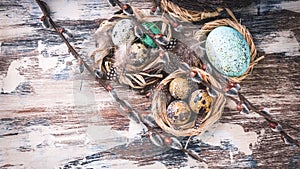 Easter eggs in nests and willow branches. Easter decorations. Rustic surface. Top view