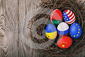 Easter eggs painted in the colors of flags different states of the world in the nest with copy space