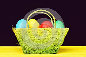 Easter eggs painted in different colours in light basket