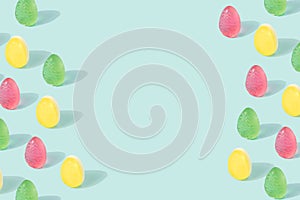 Easter eggs pattern with copy space made of colorful soft candy on a pastel blue background.
