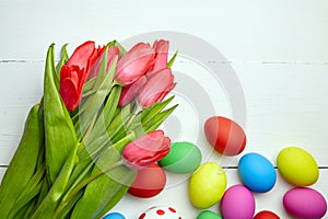 Easter Eggs and red tulip flowers on white wooden table