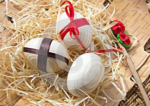 Easter eggs with ribbon and red flowers. Background birch bark and straw