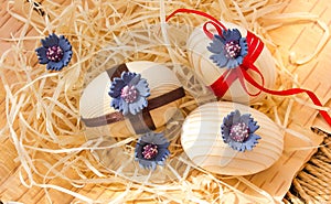 Easter eggs with ribbon and red flowers. Background birch bark and straw