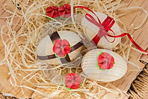 Easter eggs with ribbon and red flowers. Background birch bark and straw