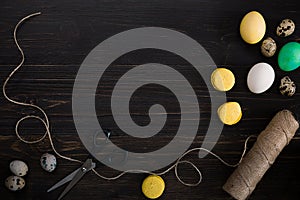 Easter eggs, scissors and thread on a black background