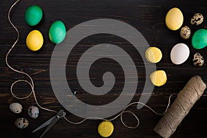 Easter eggs, scissors and thread on a black background