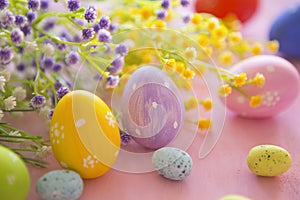 Easter eggs with spring blossom flowers on pink wooden background.