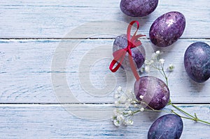 Easter eggs in trendy purple very peri color. Chicken eggs in a straw nest.