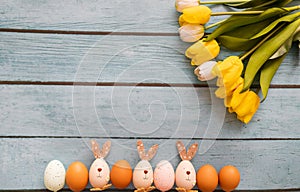 Easter eggs and tulips on blue wooden background with copy space