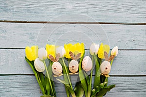 Easter eggs and tulips on blue wooden background with copy space