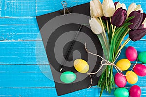 Easter eggs and tulips on blue wooden planks