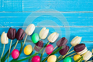 Easter eggs and tulips on blue wooden planks