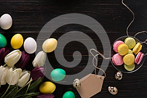 Easter eggs and tulips on dark wooden planks