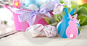 Easter eggs and tulips on wooden planks.