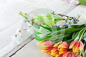 Easter eggs and tulips on wooden planks.