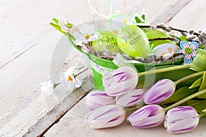 Easter eggs and tulips on wooden planks.