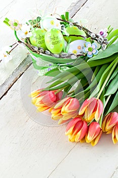 Easter eggs and tulips on wooden planks.