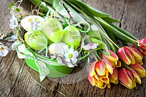 Easter eggs and tulips on wooden planks.